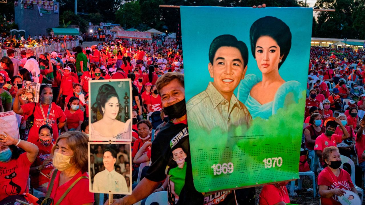 A Marcos supporter holds pictures of the late dictator Ferdinand and his wife Imelda, as Ferdinand "Bongbong" Marcos Jr. holds a campaign rally, in February this year.