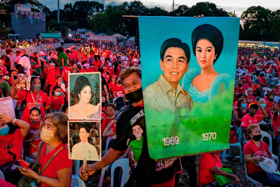 A Marcos supporter holds pictures of the late dictator Ferdinand and his wife Imelda, as Ferdinand "Bongbong" Marcos Jr. holds a campaign rally, in February this year. 
