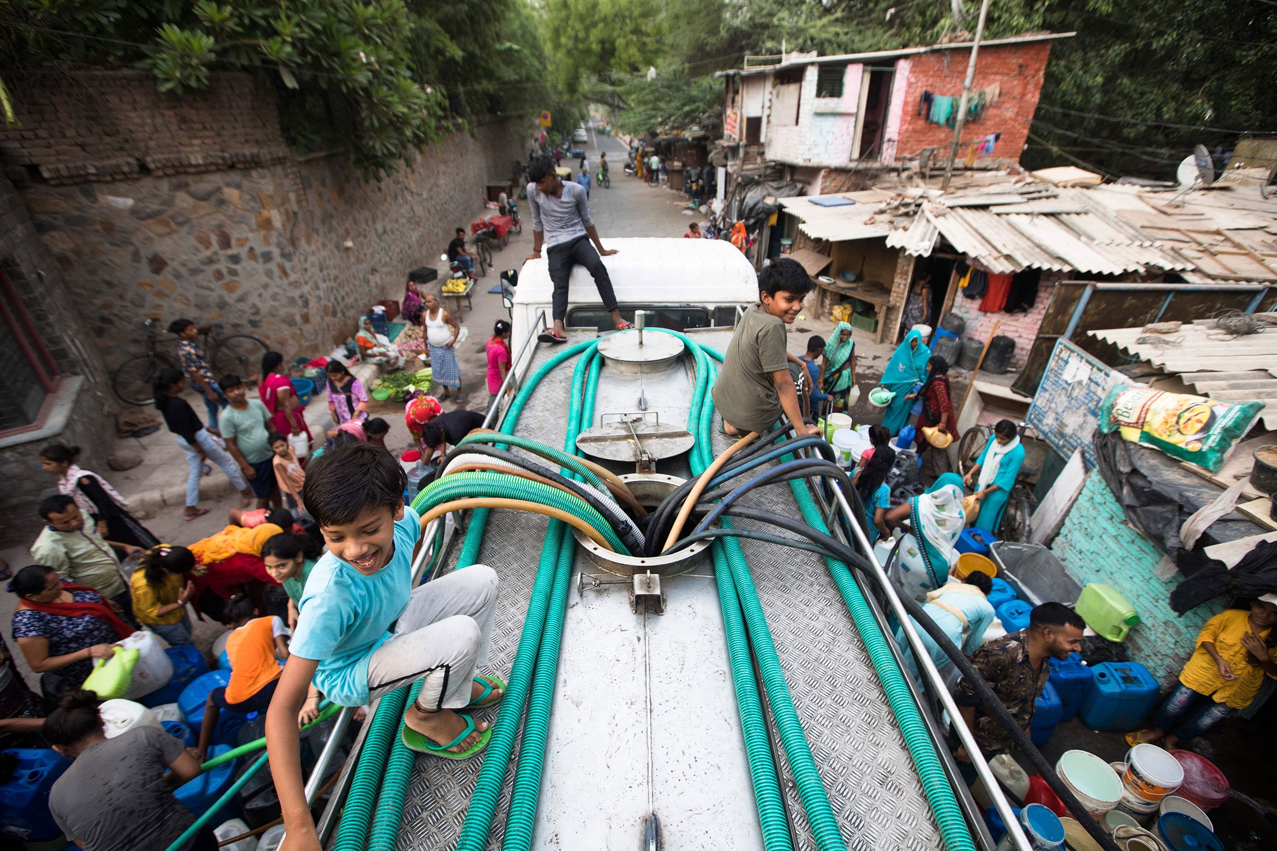 People use hoses to collect drinking water from a tanker truck during a hot day in New Delhi on Tuesday, May 3.