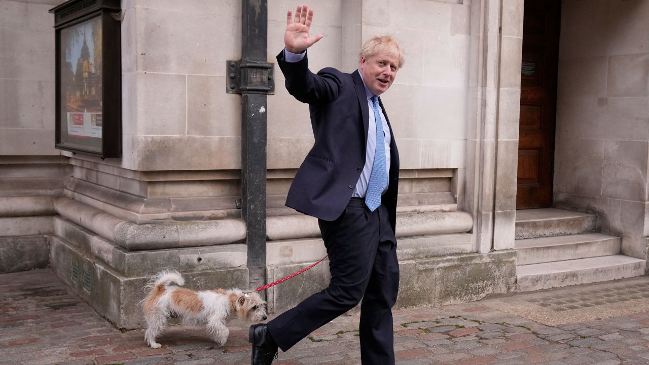 UK Prime Minister Boris Johnson waves at the media as he leaves with his dog Dilyn after voting at London polling station on May 5.