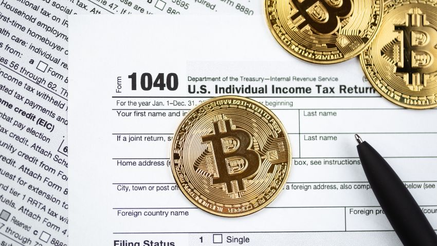 Bitcoins with US tax form 1040. Golden Bitcoin on tax form. Tax form pay concept