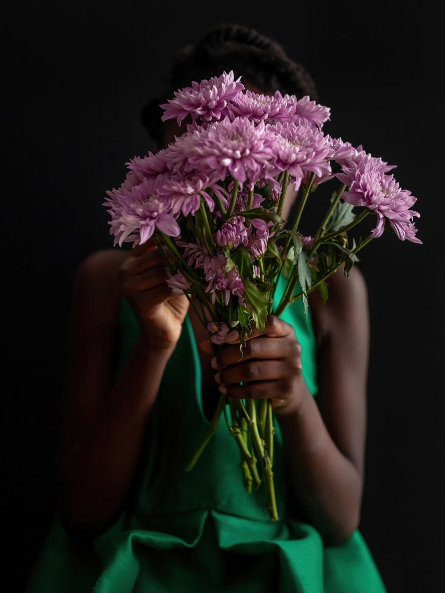 <a href="https://kareneisabelle.format.com/" target="_blank" target="_blank">Karene-Isabelle Jean-Baptiste's</a> daughter holds flowers that her grandmother brought her to cheer her up on a dreary day during the Covid-19 pandemic. "I found a vintage green dress at a Montreal thrift store years ago," Jean-Baptiste remembers. "It turns out to have been made in Canada the same year my mother was born to Haiti and many years before she would move here for a different life. Finding the dress felt serendipitous, and when my daughter dresses up in it I feel the continuity between the previous owner of the dress and my family who emigrated to Canada for a better life. My hope is that we, too, get to pass on this dress from generation to generation."