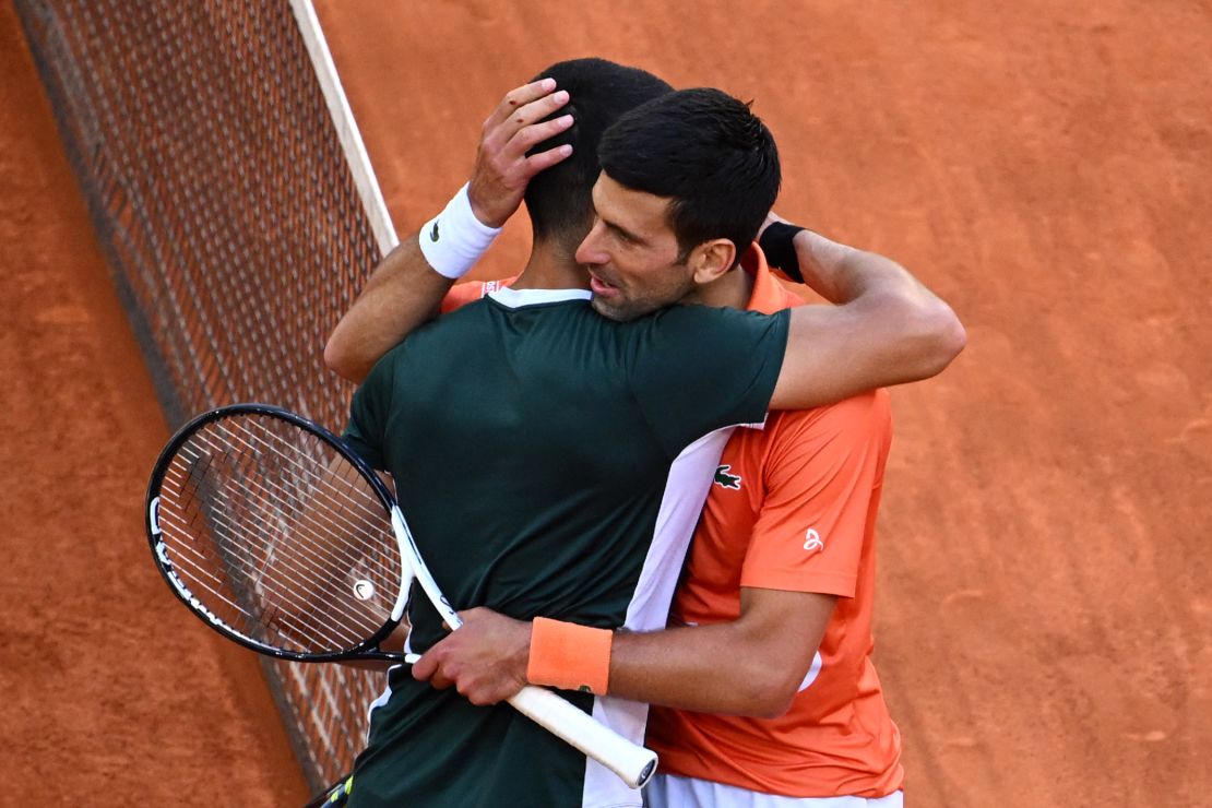 Alcaraz (L) and Djokovic hug at the end of their 2022 ATP Tour Madrid Open semifinal.