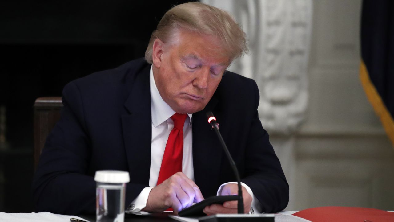 Former President Donald Trump looks at his phone during a roundtable with governors on the reopening of America's small businesses, in the State Dining Room of the White House in Washington, June 18, 2020. 