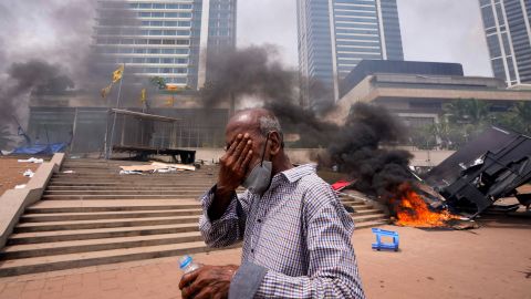 Ein Mann aus Sri Lanka schützt seine Augen vor Tränengas, als er am 9. Mai am Ort der regierungsfeindlichen Proteste in Colombo vorbeigeht.
