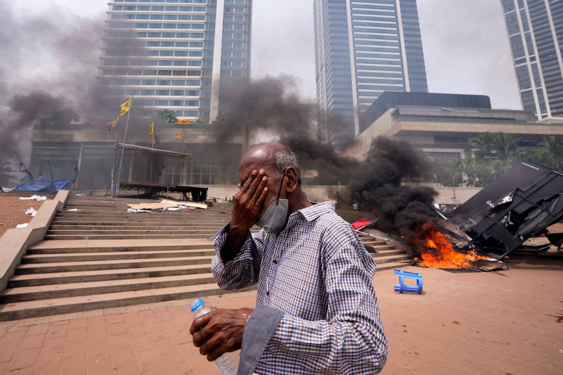 A Sri Lankan man protects his eyes from tear gas as he passes the site of anti-government protests in Colombo on May 9.