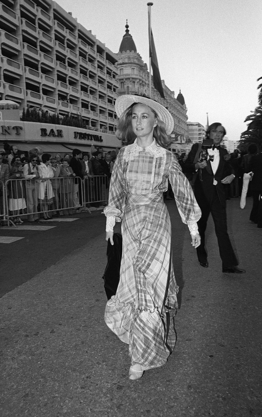 French actress Brigitte Fossey arrives at the 1977 film festival in long checked dress with lace detailing and a provincial straw hat.