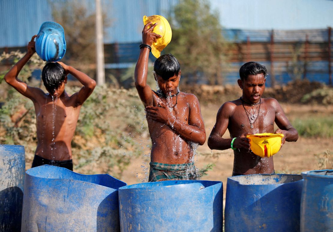 Workers use their helmets to pour water to cool themselves down as a heatwave rages in India