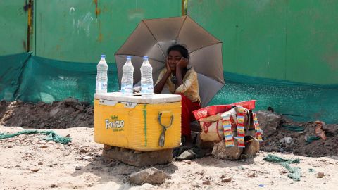 A girl selling water uses an umbrella to protect herself from the sun as she waits for customers in New Delhi, India, on April 27.