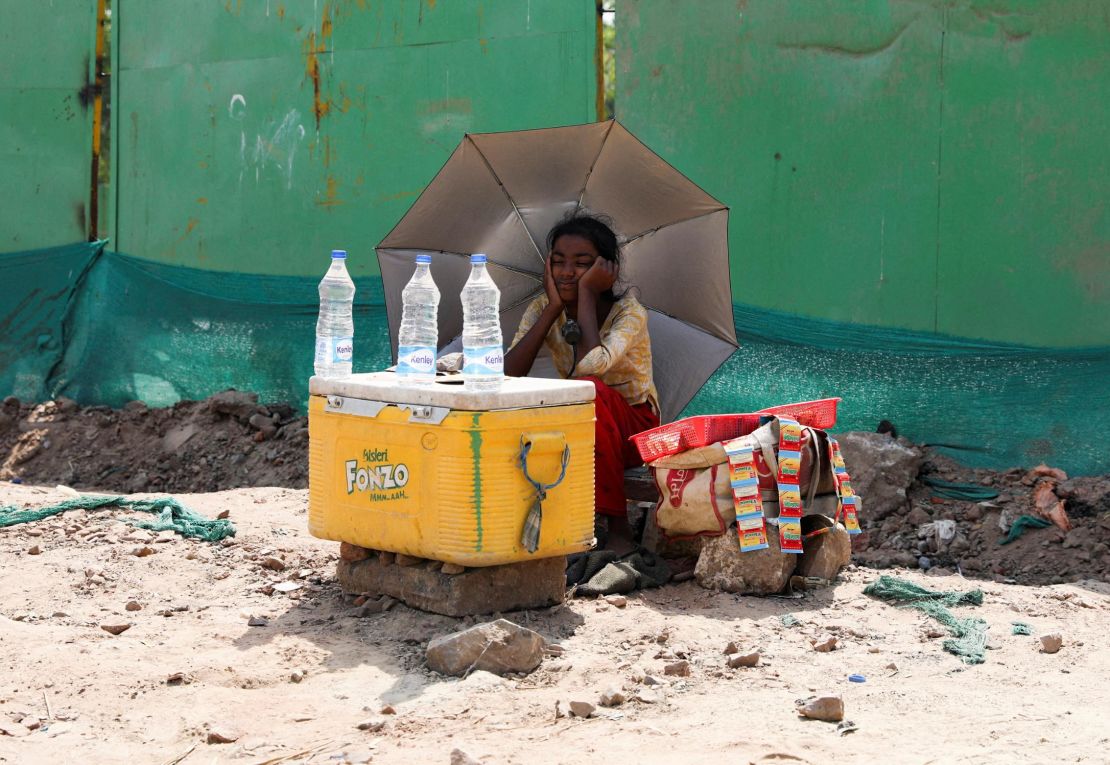 A girl selling water uses an umbrella to protect herself from the sun as she waits for customers in New Delhi, India, on April 27.