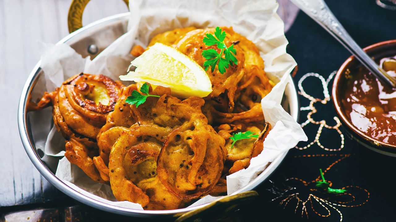 <strong>Onion bhajis (India):</strong> While there are many varieties of pakora, one special version are bhajis, or onion fritters laced with aromatic spices. This batch is served with  mango chutney.