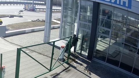 A Russian soldier approaches the vehicle dealership near Kyiv, gun drawn.