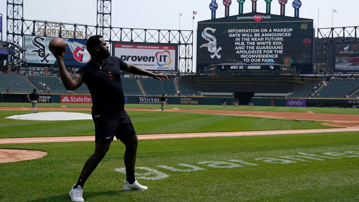Cleveland Guardians' player Franmil Reyes throws a football to teammate Myles Straw at Guaranteed Rate Field in Chicago on Wednesday.