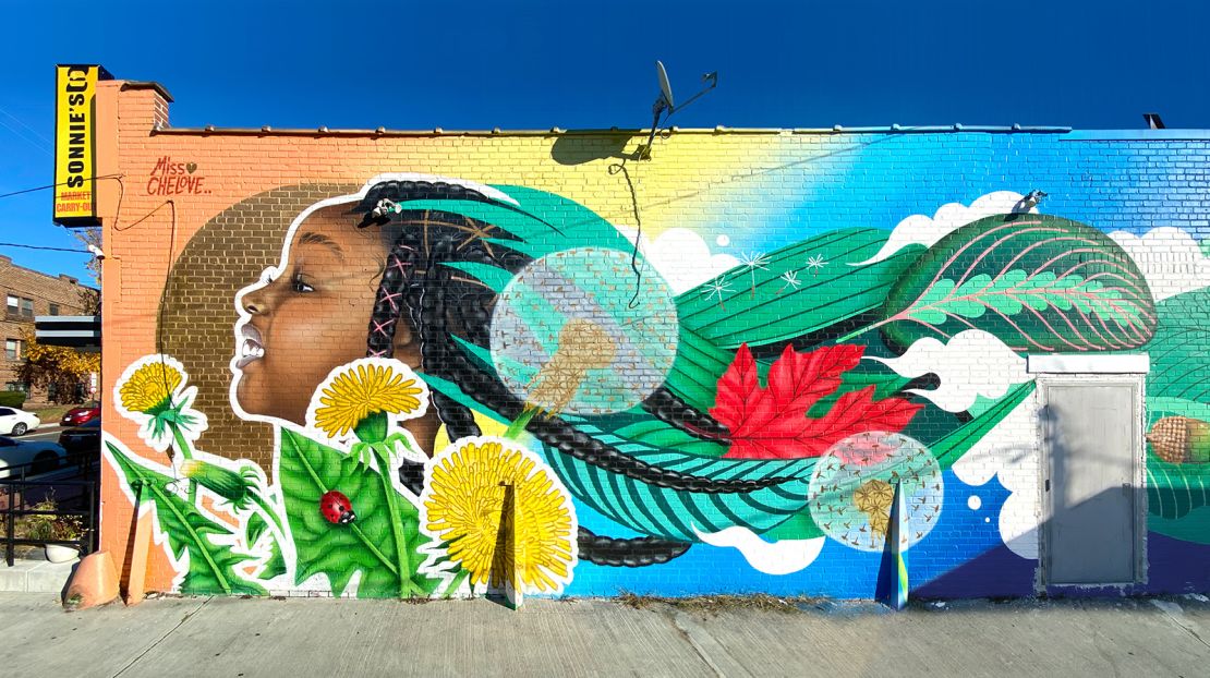 "She Smiles 100 Suns" (2019), a mural on Sonnie's Groceries in Kennedy Street, representing youth and strength.
