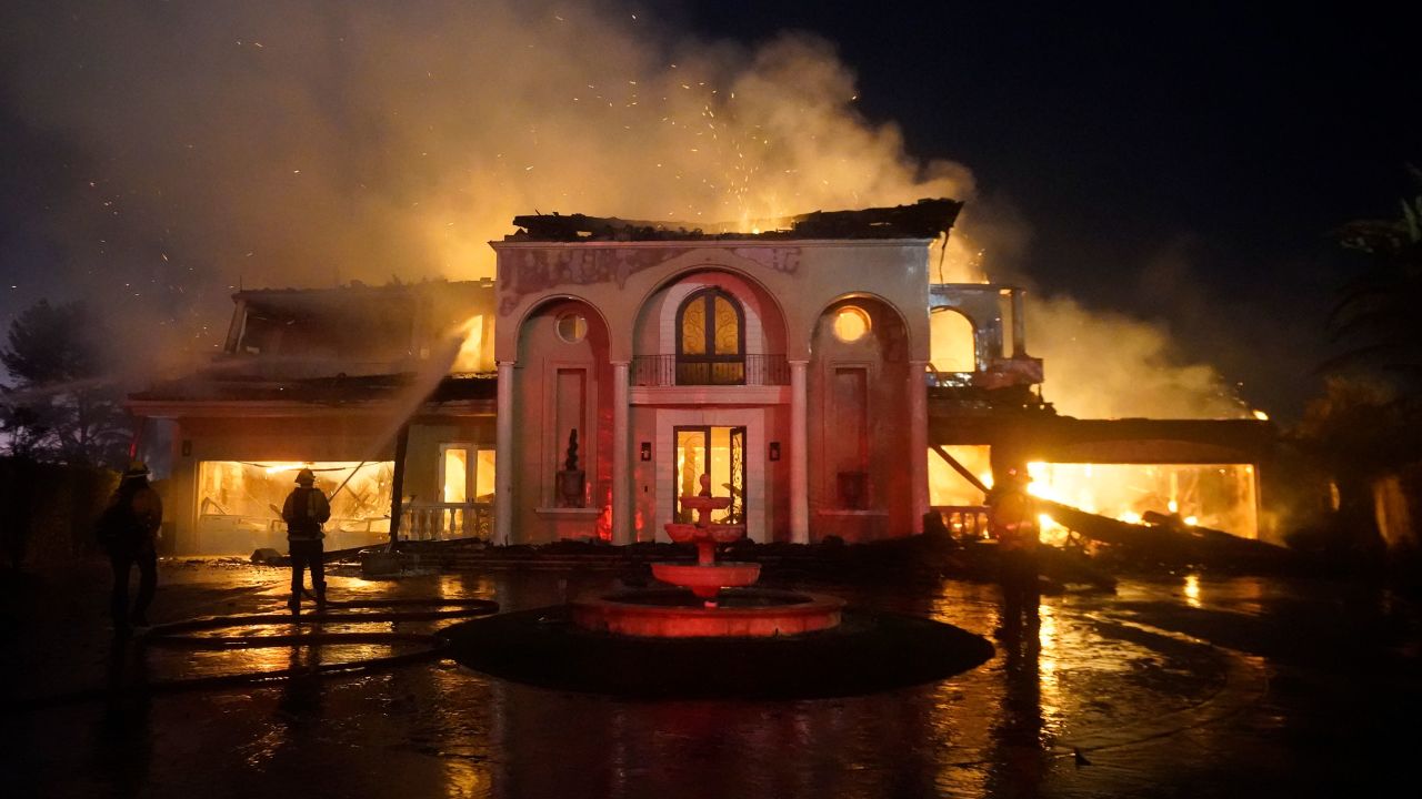 Firefighters work to put out a structure fire burning amid a wildfire Wednesday in Laguna Niguel, California.
