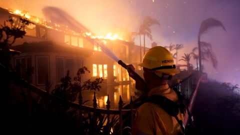 A firefighter works to put at a structure burning on Wednesday in Laguna Niguel.