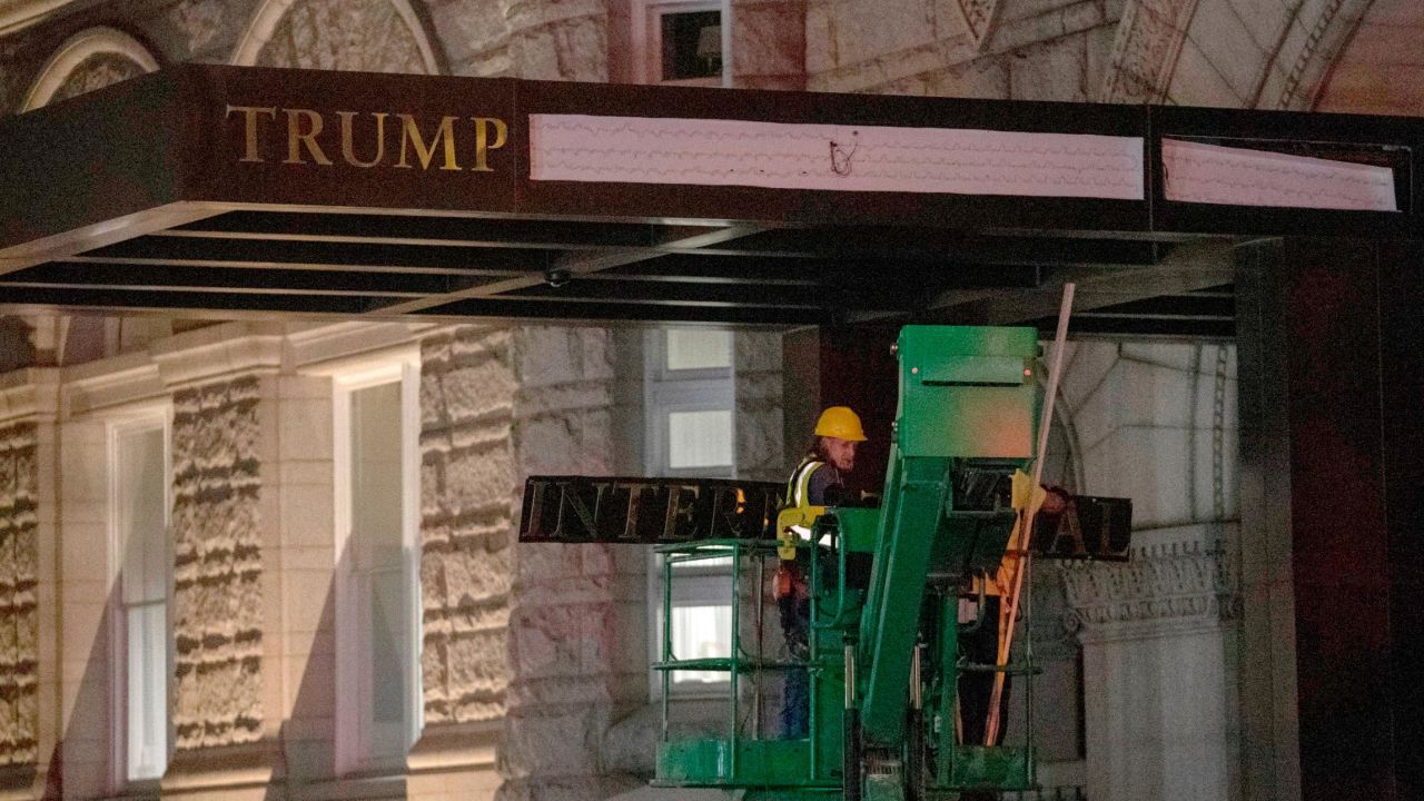 Workers remove the signage for the Trump International Hotel Wednesday, May 11, 2022, in Washington. The lease to the Washington, D.C., hotel run by Donald Trump's family company while he was president, has been sold by his family company to a Miami-based investor fund. 