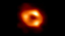 This is the first image of Sgr A*, the supermassive black hole at the centre of our galaxy, with an added black background to fit wider screens. It's the first direct visual evidence of the presence of this black hole. It was captured by the Event Horizon Telescope (EHT), an array which linked together eight existing radio observatories across the planet to form a single "Earth-sized" virtual telescope. The telescope is named after the event horizon, the boundary of the black hole beyond which no light can escape.   Although we cannot see the event horizon itself, because it cannot emit light, glowing gas orbiting around the black hole reveals a telltale signature: a dark central region (called a shadow) surrounded by a bright ring-like structure. The new view captures light bent by the powerful gravity of the black hole, which is four million times more massive than our Sun. The image of the Sgr A* black hole is an average of the different images the EHT Collaboration has extracted from its 2017 observations.  In addition to other facilities, the EHT network of radio observatories that made this image possible includes the Atacama Large Millimeter/submillimeter Array (ALMA) and the Atacama Pathfinder EXperiment (APEX) in the Atacama Desert in Chile, co-owned and co-operated by ESO is a partner on behalf of its member states in Europe.