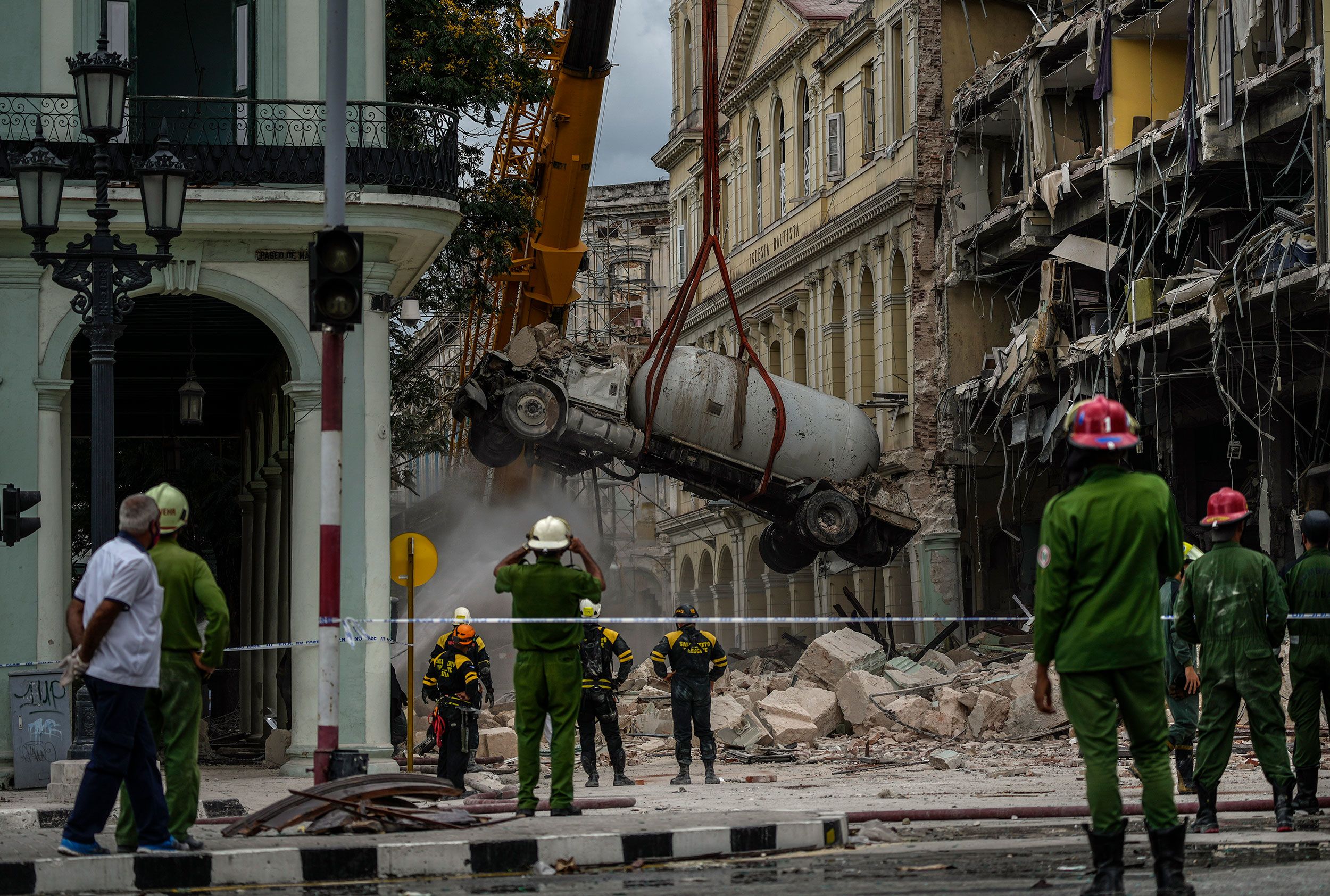 Firefighters spray a tanker truck with water to cool it down as it is removed from the site of an explosion that destroyed the Hotel Saratoga in Havana, Cuba.