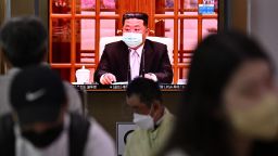 People sit near a screen showing a news broadcast at a train station in Seoul on May 12, 2022, of North Koreas leader Kim Jong Un appearing in a face mask on television for the first time to order nationwide lockdowns after the North confirmed its first-ever Covid-19 cases.