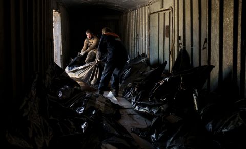 A Ukrainian serviceman and a worker carry the body of a Russian soldier into a refrigerated train in Kharkiv, Ukraine, on Thursday, May 5. The bodies of more than 40 Russian soldiers, found after battles around Kharkiv, were being stored in the refrigerated car.
