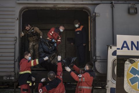 Ukrainian serviceman and emergency workers carry the body of a Russian soldier into a refrigerated train in Kharkiv, Ukraine, on May 5. The bodies of more than 40 Russian soldiers who were found after battles around Kharkiv are being stored in the refrigerated car. 