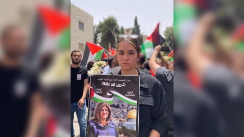 Shireen Abu Akleh's niece, Lareen, 19,  at her aunt's funeral procession in Jerusalem. Her poster reads: 
