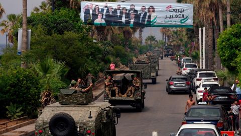 Veículos do exército libanês passam por um outdoor representando candidatos na eleição geral de domingo, 14 de maio, em Beirute, Líbano.