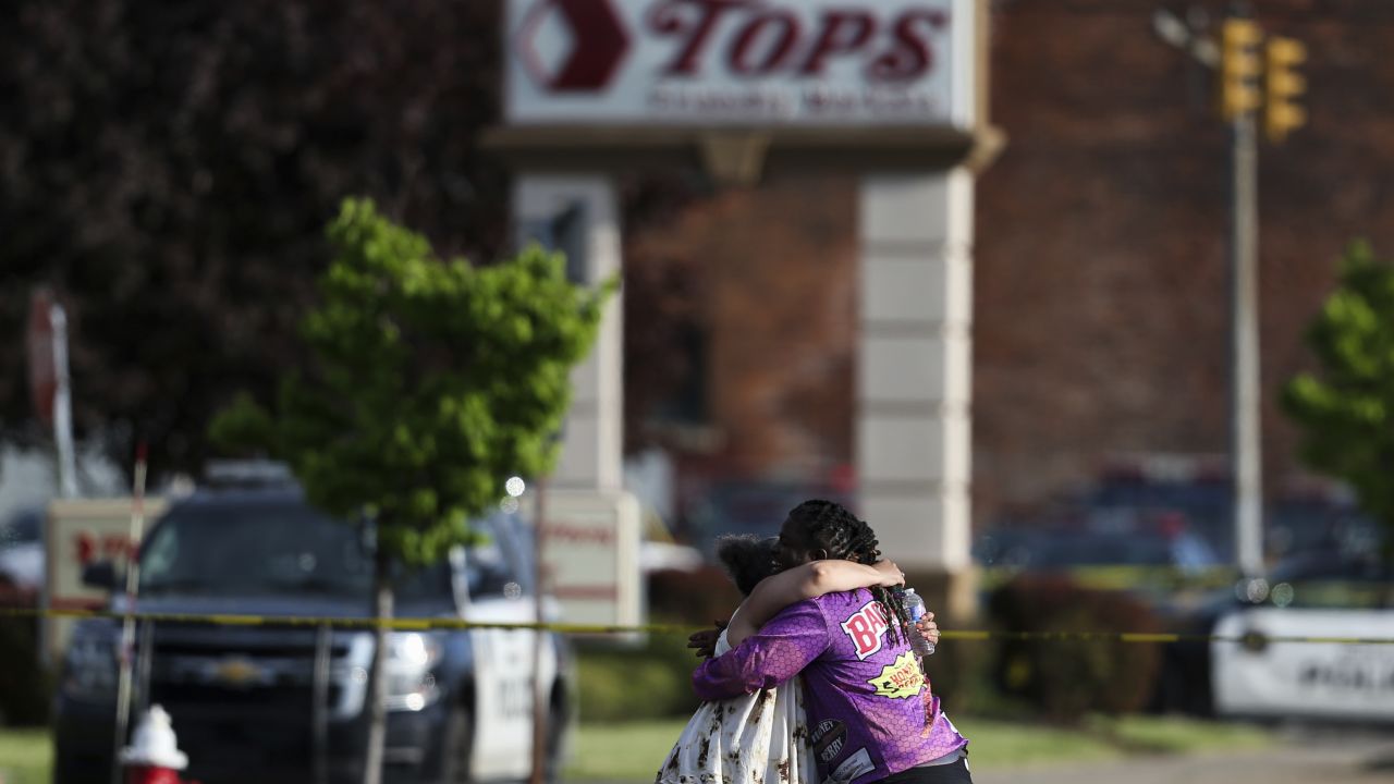 People hug near the scene of the mass shooting at the Tops Friendly Markets store Saturday.