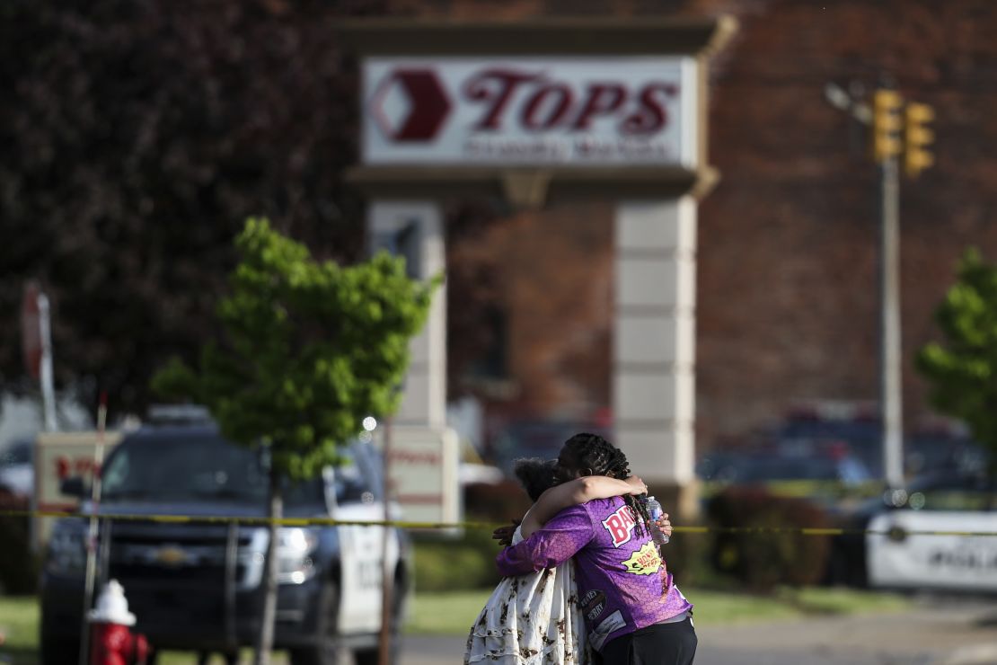 People hug near the scene of the mass shooting at the Tops Friendly Markets store Saturday.