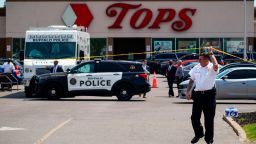 A police officer lifts the tape cordoning off the scene of a shooting at a supermarket, in Buffalo, N.Y., Sunday, May 15, 2022.
