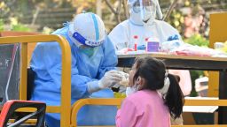 ШАНХАЙ, КИТАЙ - 09 АПРИЛ: Медицински работник взема проби от нуклеинова киселина от дете в затворен комплекс, след като Шанхай наложи блокиране в целия град, за да спре разпространението на епидемията от COVID-19 на 9 април 2022 г. в Шанхай, Китай.  (Снимка от Shen Chunchen/VCG чрез Getty Images)
