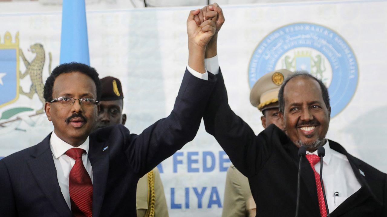 Somalia's newly elected president Hassan Sheikh Mohamud (right) holds hands with incumbent president Mohamed Abdullahi Mohamed (left) after winning the elections in Mogadishu, Somalia May 16, 2022.