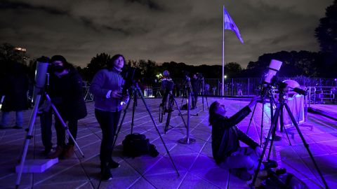 Lidé v Buenos Aires pozorují Měsíc dalekohledy v pondělí brzy během úplného zatmění Měsíce. 