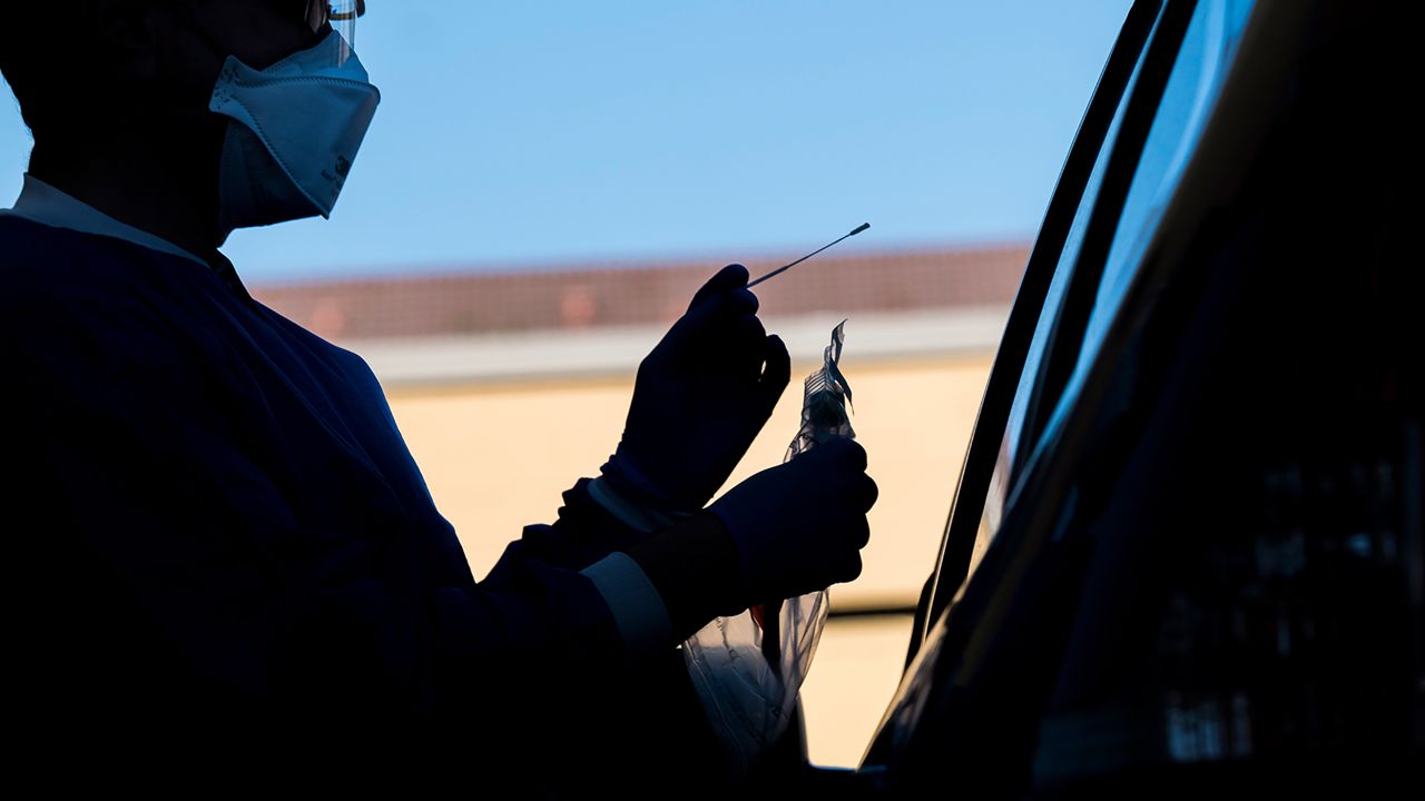 A medical personnel wearing personal protective equipment (PPE) is silhouetted while administering a swab test at a COVID-19 drive-thru testing site in San Pablo, California, U.S., on Tuesday, April 28, 2020. California, which has closed schools for the academic year, is considering bumping up the start of the new school year to late July or early August, Governor Gavin Newsom said. Photographer: David Paul Morris/Bloomberg via Getty Images