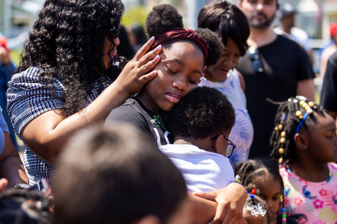 People surround Deazjah Roseboro, 12, as she comforts her 8-year-old cousin, Jerney Moss.