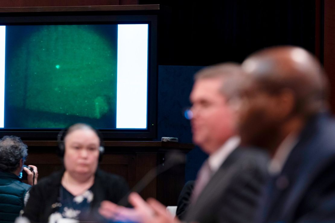 Under Secretary of Defense for Intelligence and Security Ronald Moultrie, right, and Deputy Director of Naval Intelligence Scott Bray speak with a UAP on a screen.