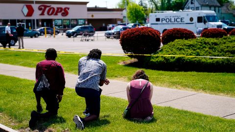 People pray outside the scene of Saturday's shooting at the Tops supermarket in Buffalo.