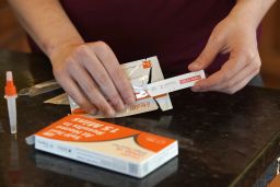 A  worker prepares one of the new government-issued Covid-19 Antigen Rapid test kits she received to take a self-test while at home on February 8 in Provo, Utah. 