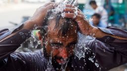 A man uses a water pipe to cool off in Karachi.
