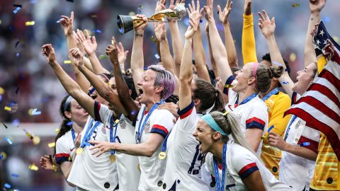 Megan Rapinoe lifts the FIFA Women's World Cup trophy as her team celebrates winning the 2019 edition of the tournament. 