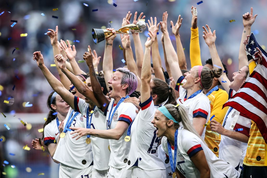 Megan Rapinoe lifts the FIFA Women's World Cup trophy as her team celebrates winning the 2019 edition of the tournament. 