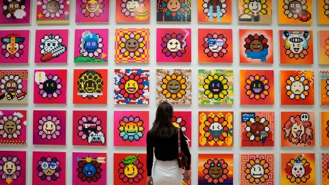 A person stands in front  of artist Takashi Murakami's NFT project called Murakami Flowers.