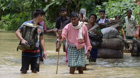 Pessoas atravessam as águas da enchente no distrito de Nagoon, no estado indiano de Assam, em 18 de maio.