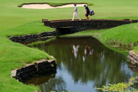 Rory McIlroy et le caddy Harry Diamond traversent un pont au troisième trou lors d'une ronde d'entraînement avant le début du championnat PGA 2022.