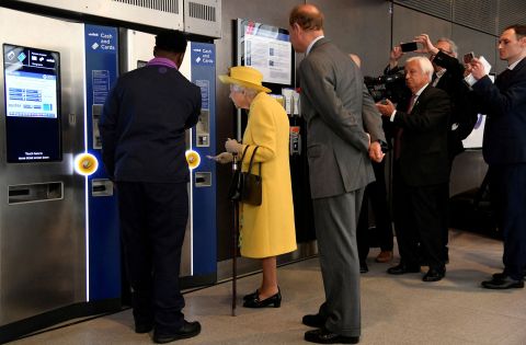 Britain's Queen Elizabeth II is shown how to purchase a train ticket as she attends <a href=