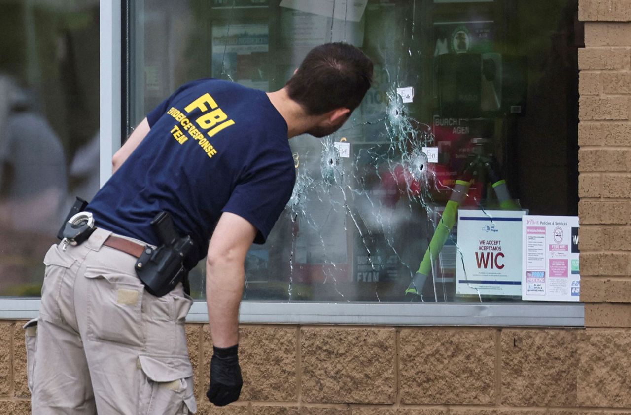 A member of the FBI looks at bullet holes at the scene of the shooting at <a href="https://www.cnn.com/2022/05/19/us/buffalo-supermarket-shooting-thursday/index.html" target="_blank">Tops supermarket</a> in Buffalo on Monday, May 16.