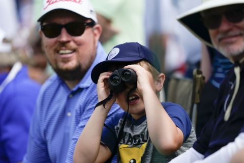 A young spectator views players through binoculars during the second round.