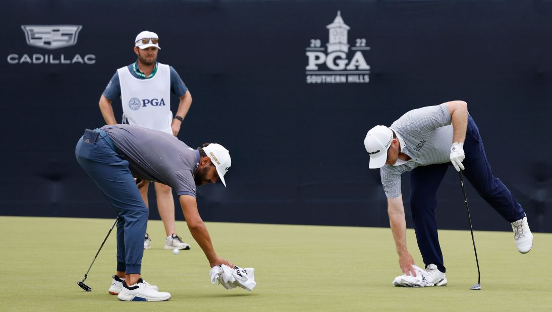 Erik van Rooynen (left) and Harry Higgs (right) clean off the green on the 12th hole during the second round.