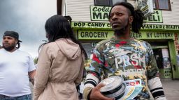 Julie Harwell (left in beige jacket) and Lamont Thomas observe their surroundings on Jefferson Avenue .The couple told us they were in the store during the shooting as they avoided the gunman's wrath and hid their 8-year-old daughter in a freezer. 5/18/22